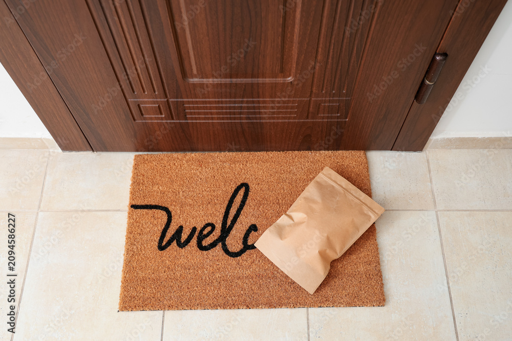 Obraz premium Paper bag on mat near door in hallway, top view. Delivery service