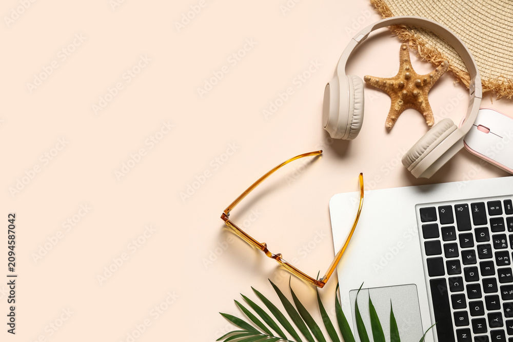 Obraz premium Laptop with headphones, mouse and beach accessories on beige background