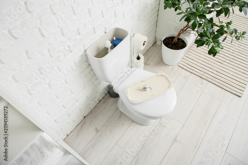 Toilet bowl with removed tank lid and water in light restroom
