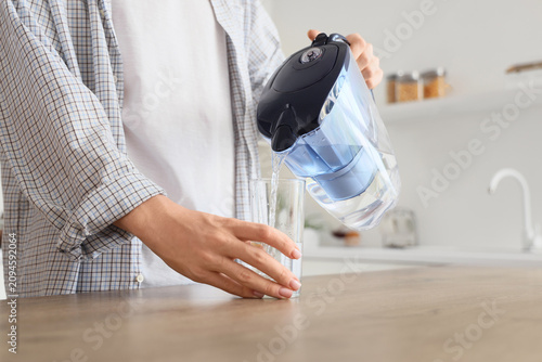 Young man pouring water fro...