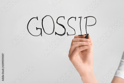 Quadro su tela Woman writing word GOSSIP on glass against light background, closeup