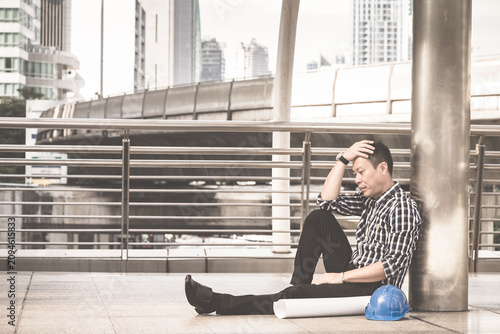 Asian engineer man who sitting on the floor in feeling sad because his business failed and unemployed. Business failed concept.