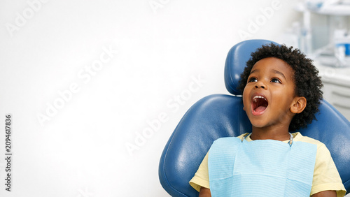 A smiling young boy at the dentist for a check-up, ready to be examined by the dentist.