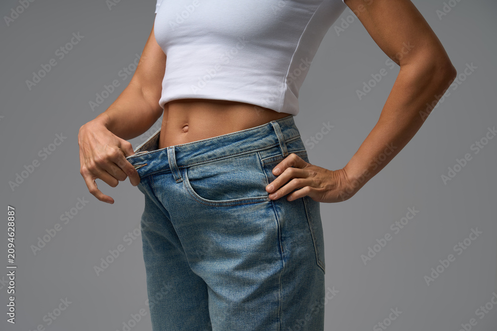 Obraz premium Slim woman confidently posing in white crop top after weight loss achievement