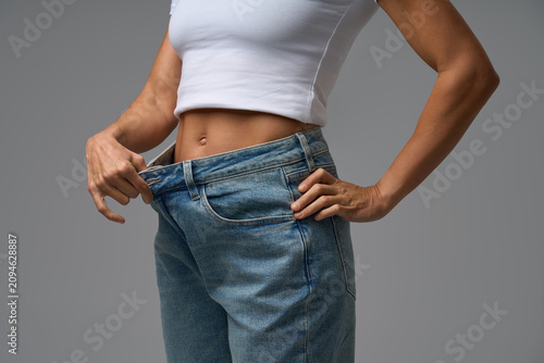 Slim woman confidently posing in white crop top after weight loss achievement