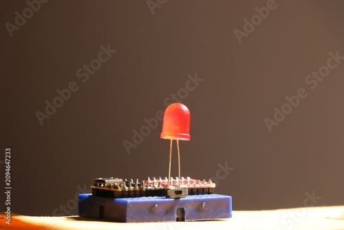 Red led connected on blue circuit board with microcontroller for electronics project