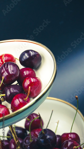 Gourmet presentation of ripe summer cherries on a minimalist two-tiered serving stand
