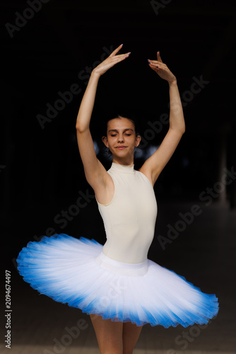 Foto Ballet dancer in white leotard and blue-tipped tutu performing graceful pose wit