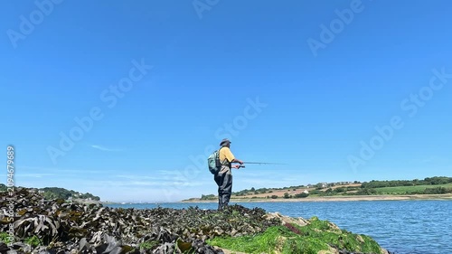 Un pêcheur à la canne à lancer sur le bord d'une rivière en Bretagne