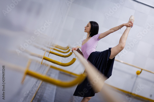 Tableau sur toile Ballet dancer stretches at a barre in a studio during a dance class on a weekday
