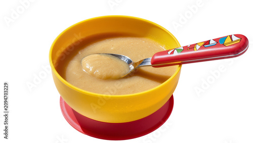 Isolated healthy and nutritious baby food puree in a bright yellow bowl with a colorful spoon.