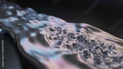 Flowing colors move across a surface in a dark background