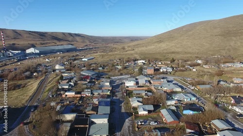 4K aerial drone footage flying over Julia Dufour, a Patagonian megausina in Santa Cruz, Argentina. Scenic urban landscape surrounded by rugged mountains, showcasing the beauty of southern Patagonia.