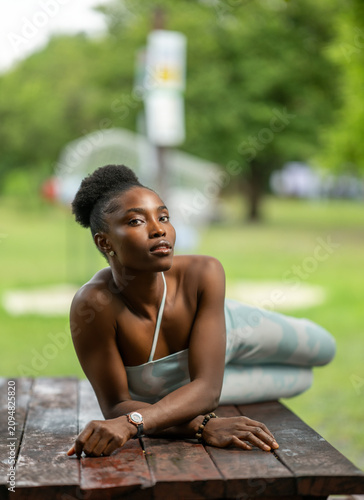Portrait of a young African woman laying on a park bench
