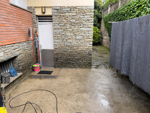 Schilderij op canvas Wet concrete patio with stone walls and cleaning tools in Olot