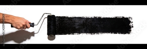 A hand holding a paint roller is painting horizontal black lines on a white background.