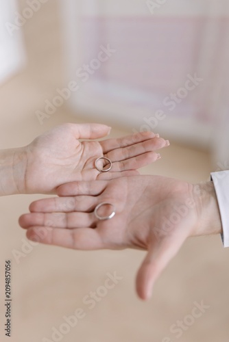 Close-up view of bride and groom hands holding wedding rings on open palms