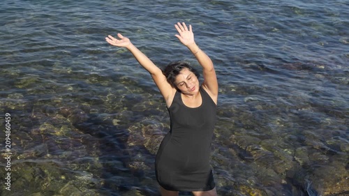 Happy woman expressing freedom and joy in the Mediterranean sea embracing freedom and wellbeing