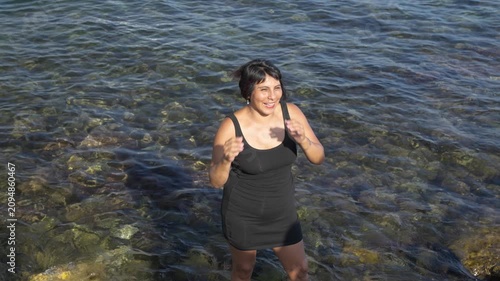 Joyful woman dancing and laughing in the sea celebrating happiness, freedom and wellbeing