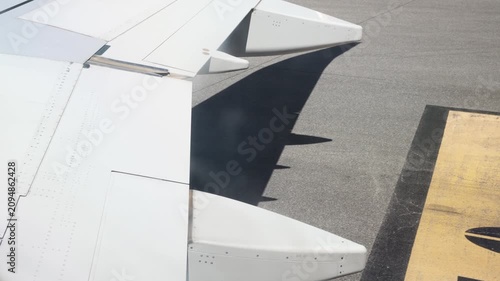 Airplane wing flaps extending on an airport runway during commercial air travel and tourism