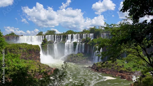 Dynamic capture of water in motion cascading over the rocky cliffs of Iguazu Falls; a vast, natural spectacle in South America with verdant jungle foliage framing the scene