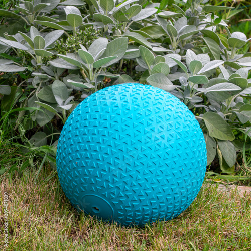 heavy rubber slam ball filled with sand in a backyard, exercise and fitness concept