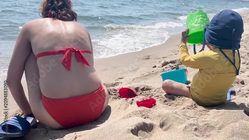 Mother and child playing with sand on a sunny beach