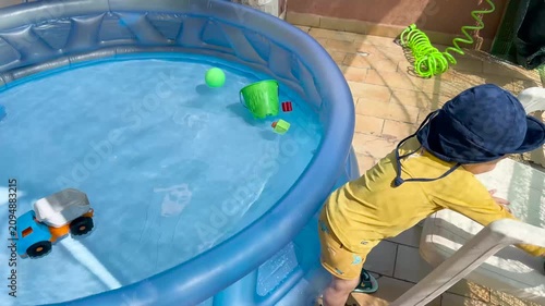 Toddler playing with toys in an inflatable swimming pool on a balcony