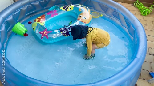 Toddler playing in an inflatable swimming pool