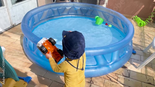 Toddler playing with a toy truck near an inflatable pool