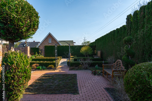Foto Inviting Backyard Garden with Pathway, Manicured Hedges, and Rustic Bench Under