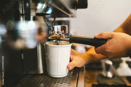 Φωτογραφία Barista pulling a fresh espresso shot into a white cup using a professional coffee machine in a modern specialty coffee shop