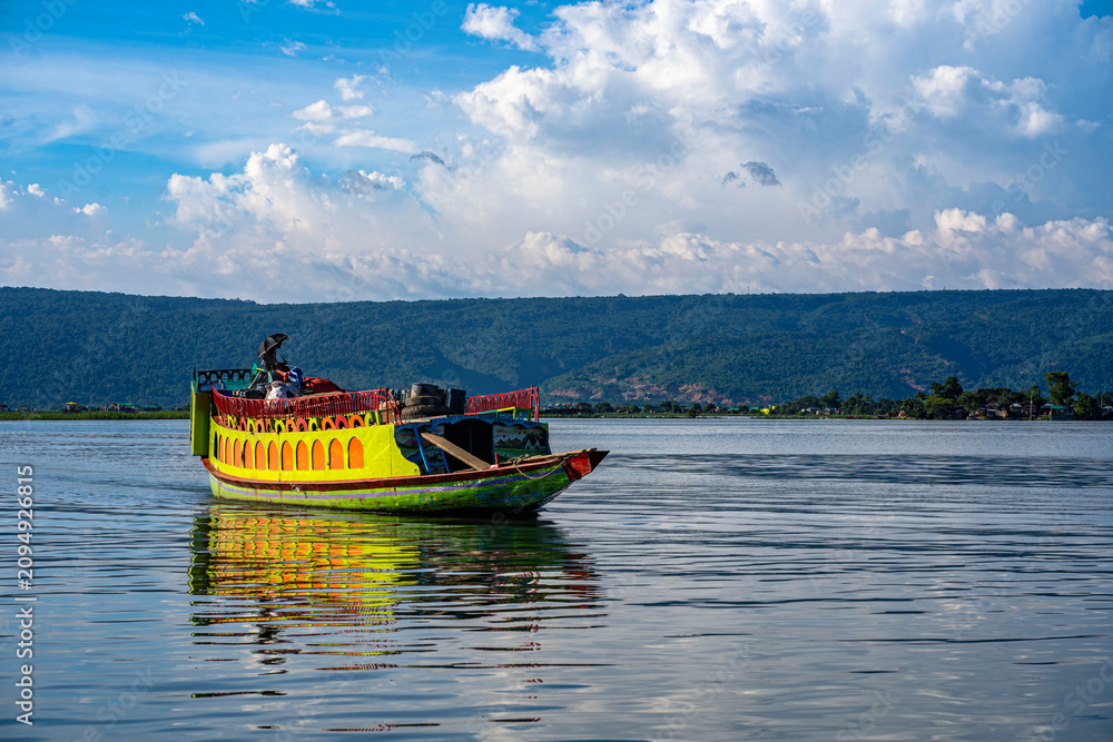 Fototapeta premium A scenic view of traditional and modern luxury houseboats carrying tourists across the vast freshwater wetland of Tanguar Haor in Sunamganj, Bangladesh, under a bright blue sky.