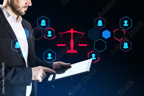 Tableau sur toile Businessman using tablet with glowing red scales of justice and people icons in hexagons on dark blue background illustrating law, injustice and ethics