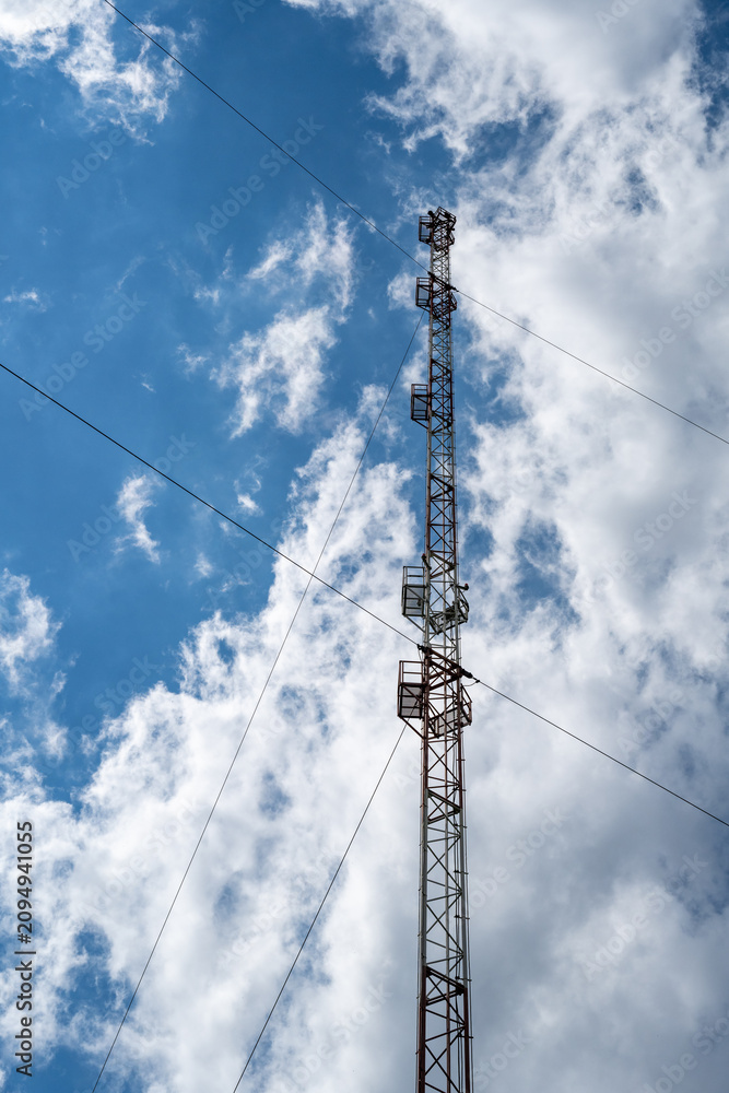 Obraz premium High Voltage Power Transmission Tower and Electrical Lines Against Blue Sky with Industrial Steel Pylon, Energy Infrastructure and Communication Technology Background