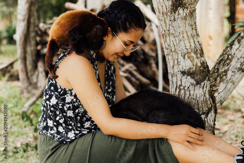 Foto Mujer feliz al aire libre interactuando con un pequeño mono y un coatí con cariño, celebrando la conexión con la fauna en el Día Mundial de los Animales