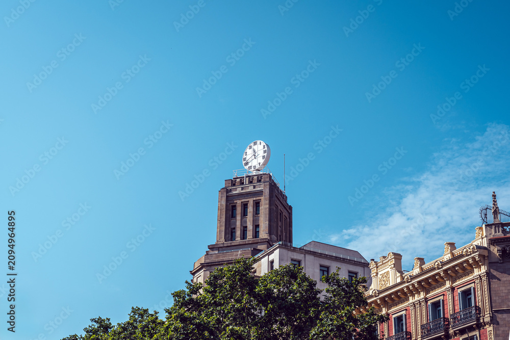 Obraz premium Historic clock tower on ornate building against blue sky in Barcelona