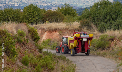 Photos Tractor with grape harvester traveling rural road for wine production