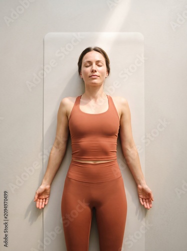 Woman practicing shavasana yoga relaxation pose overhead view