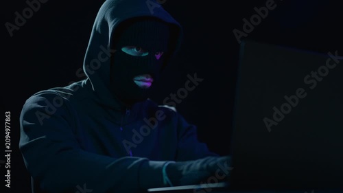 Hacker works on computer in darkness