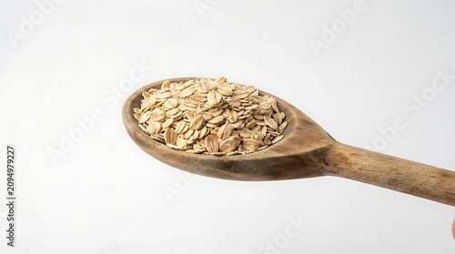 Wooden spoon filled with whole grain oats on white background