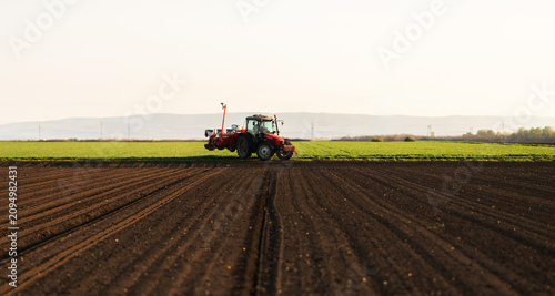 Modern tractor planting corn with precision seeder on agricultural field
