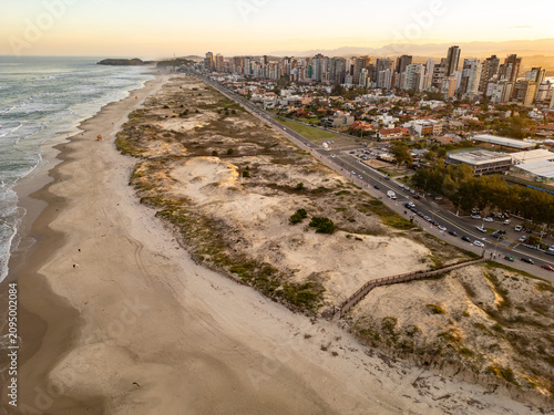 Drone View of Torres Beach with Dunes, Vegetation and City Buildings at Sunset, Brazil