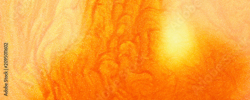 Shimmering gold abstract background. Liquid gold texture waves and swirls. Beautiful shiny yellow texture with glitter. Liquid gold metallic paint close-up.