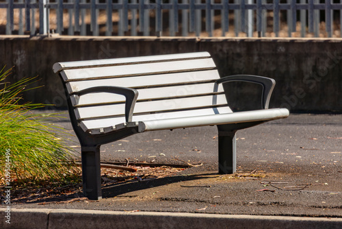 Photograph of a public bench seat located on a footpath near a road and bus stop in a major urban area of greater Western Sydney in New South Wales, Australia
