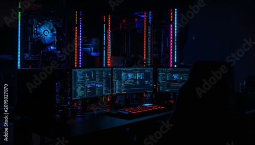 Workstation Setup With Multiple Monitors in Dark Room With Colorful Lights at...