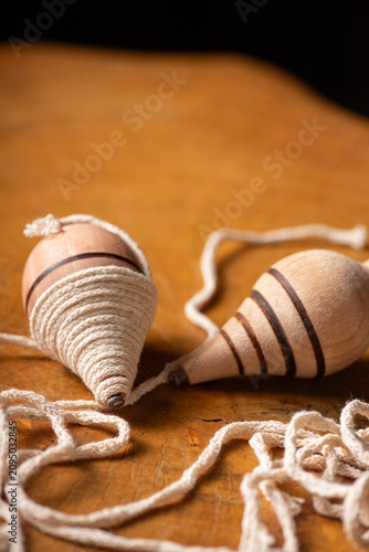 Wooden spinning top; beautiful details of a wooden spinning top placed on a rustic wooden surface, selective focus.