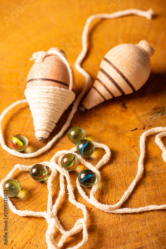 Marbles and spinning tops; beautiful details of marbles and spinning tops placed on a rustic wooden surface, selective focus.