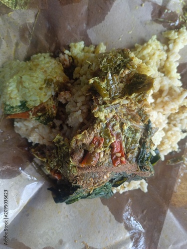 Savory Meal nasi padang Wrapped in Paper.  Indonesian padang food or nasi bungkus with beef rendang, casava leaf, green chili sauce. Semarang, 12-07-2026
