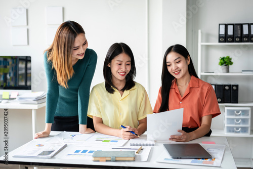 Three women are sitting at a table with papers and a laptop